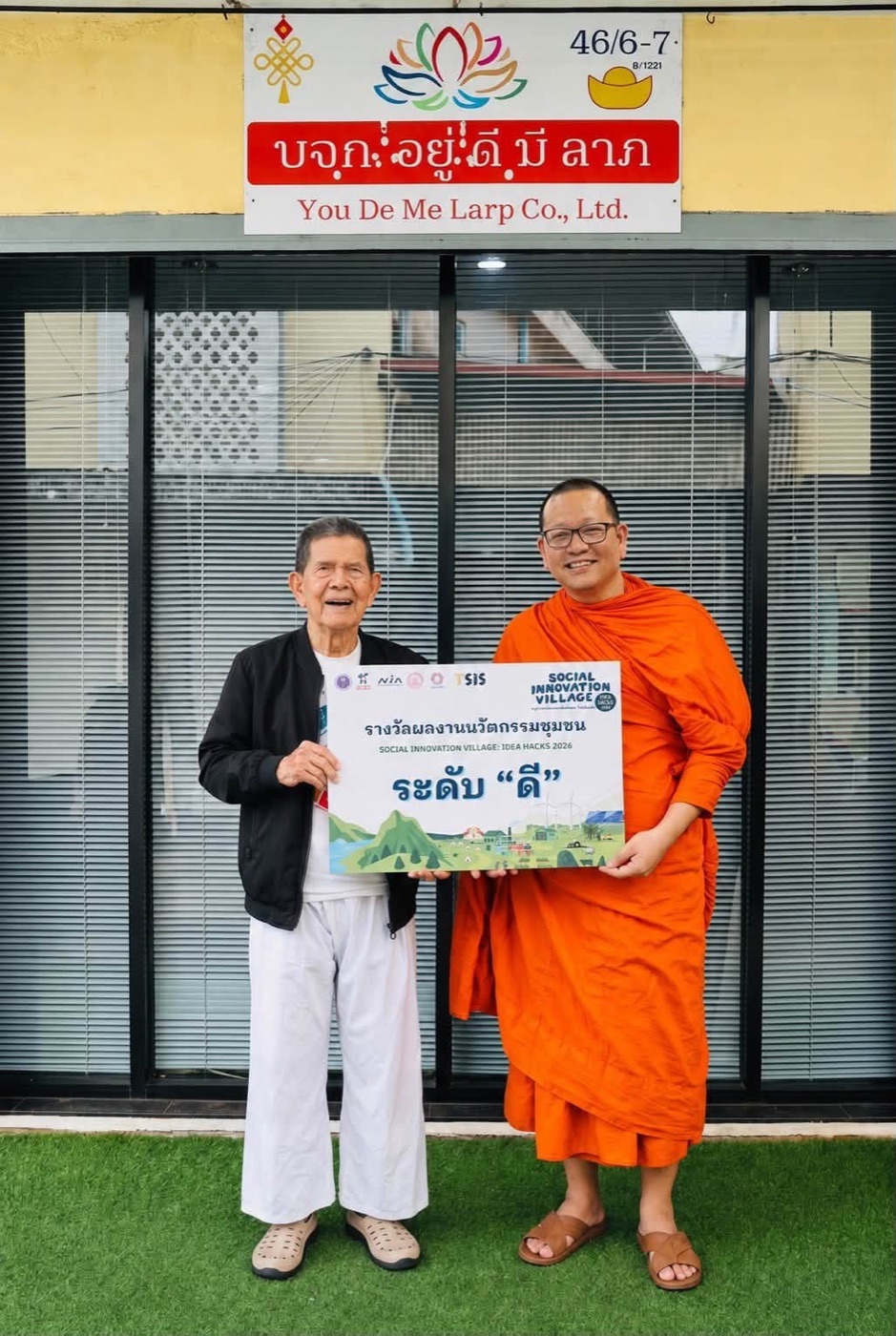 พระอาจารย์และผู้ร่วมงานกับป้ายรางวัลนวัตกรรมชุมชน